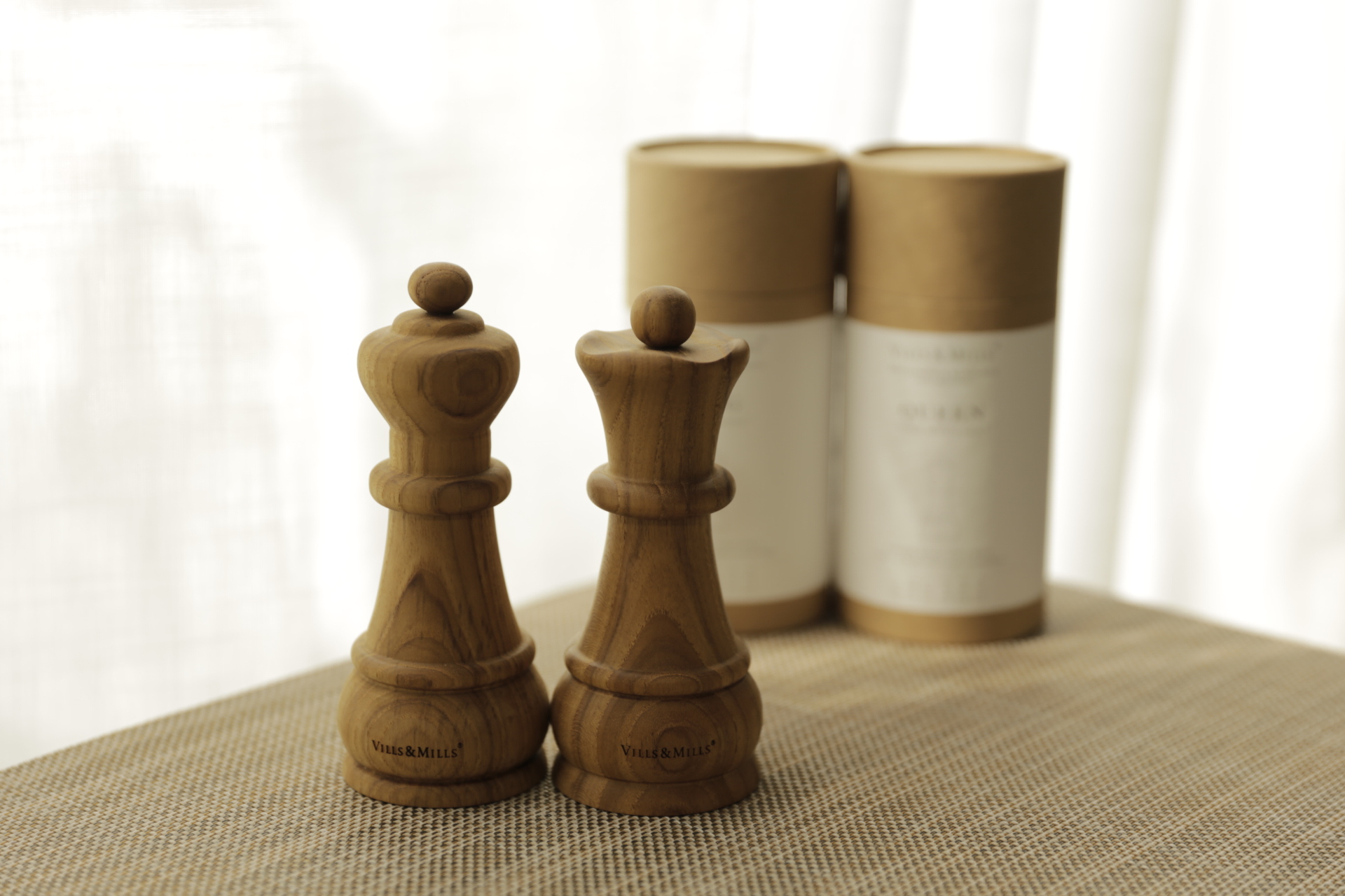 King and Queen salt and pepper mills in solid teak beside their KING and QUEEN packaging tubes
