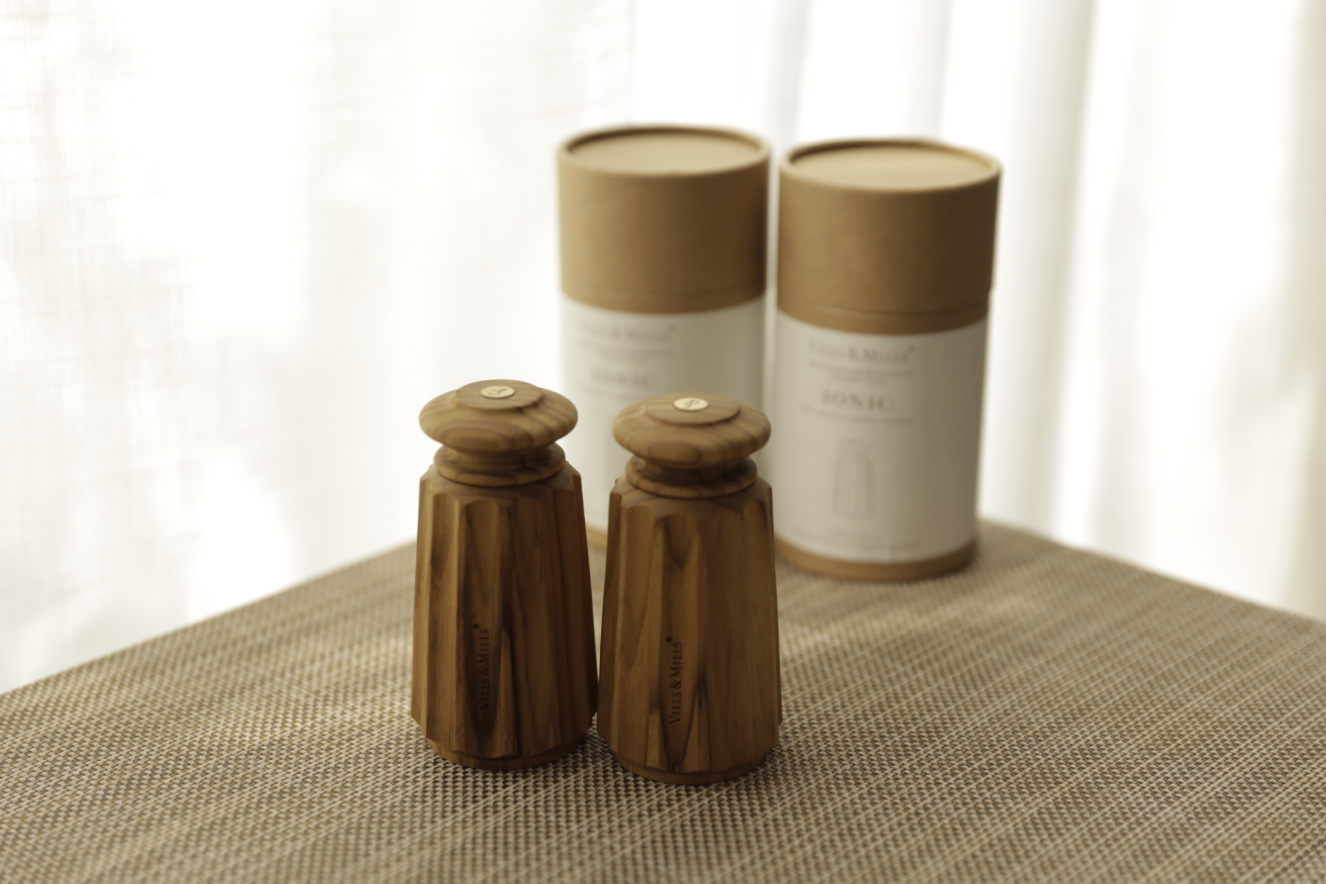 Ionic salt and pepper mills — tapered teak bodies with round knob tops beside their IONIC packaging tubes