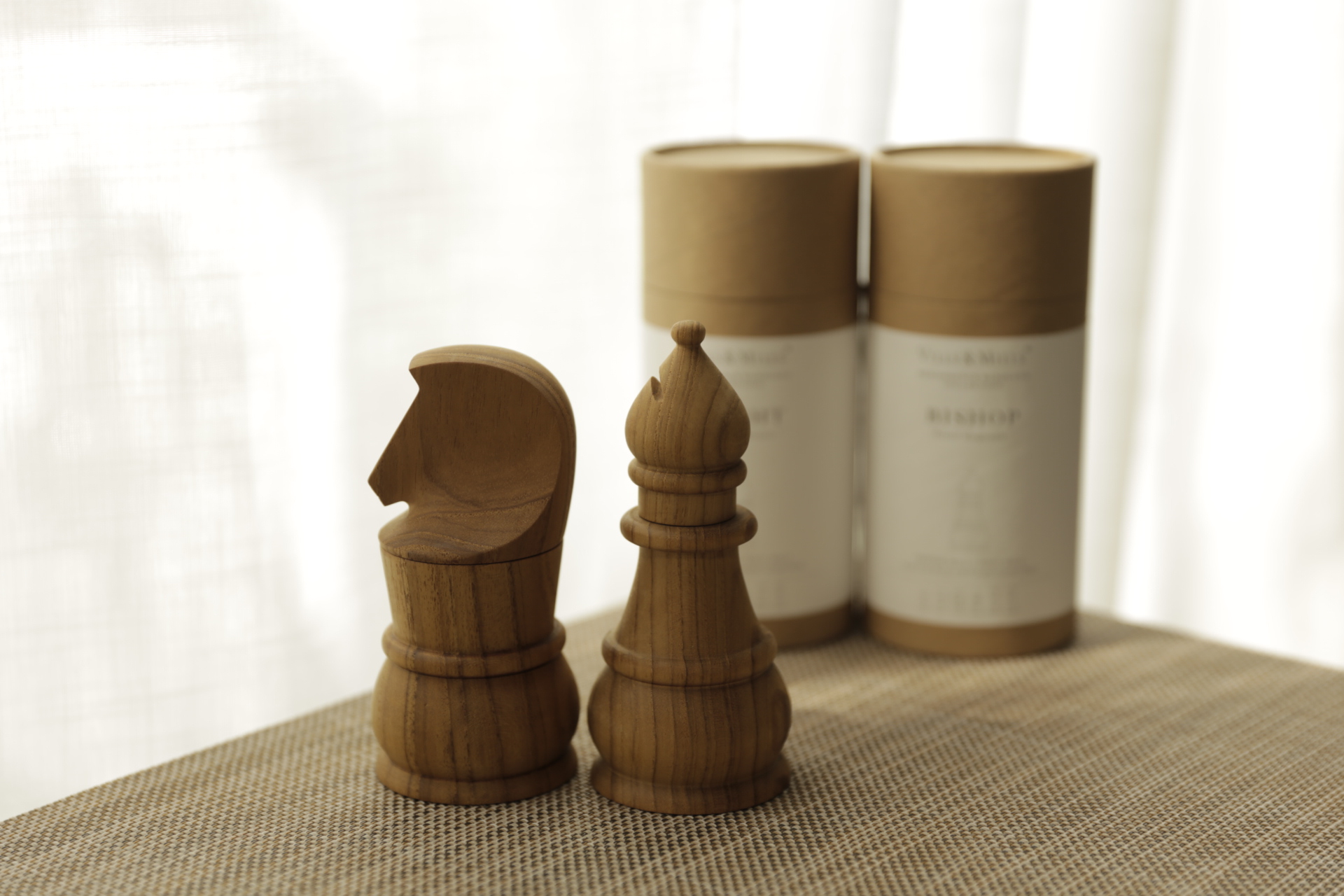 Knight and Bishop salt and pepper mills in solid teak beside their KNIGHT and BISHOP packaging tubes