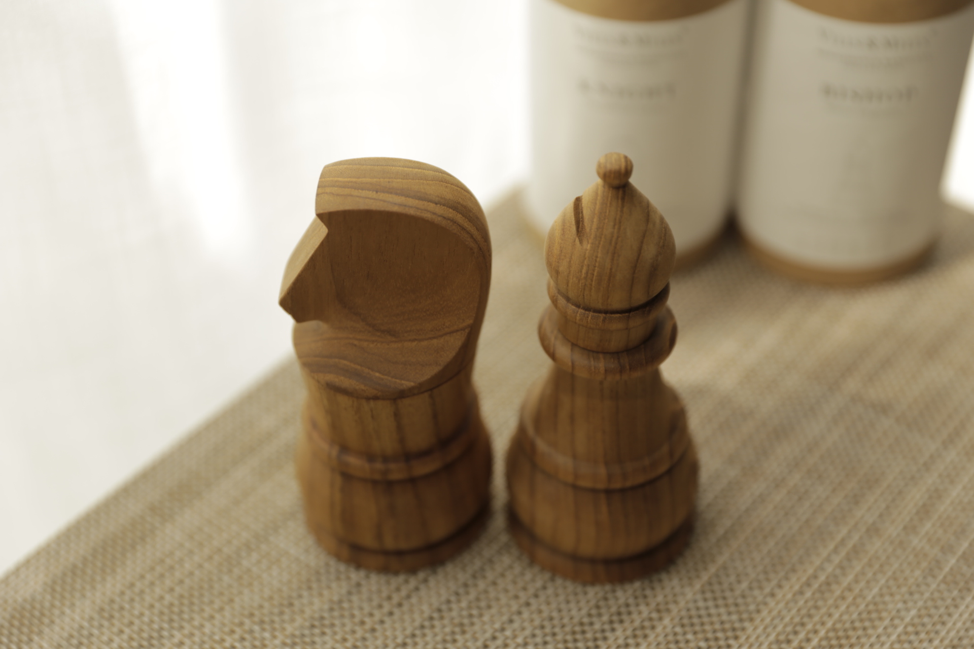 Hand-carved wooden chess knight and bishop pieces resting on a woven placemat